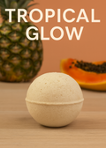 Bath bomb with pineapple and papaya on a wooden surface, labeled 'Tropical Glow'.